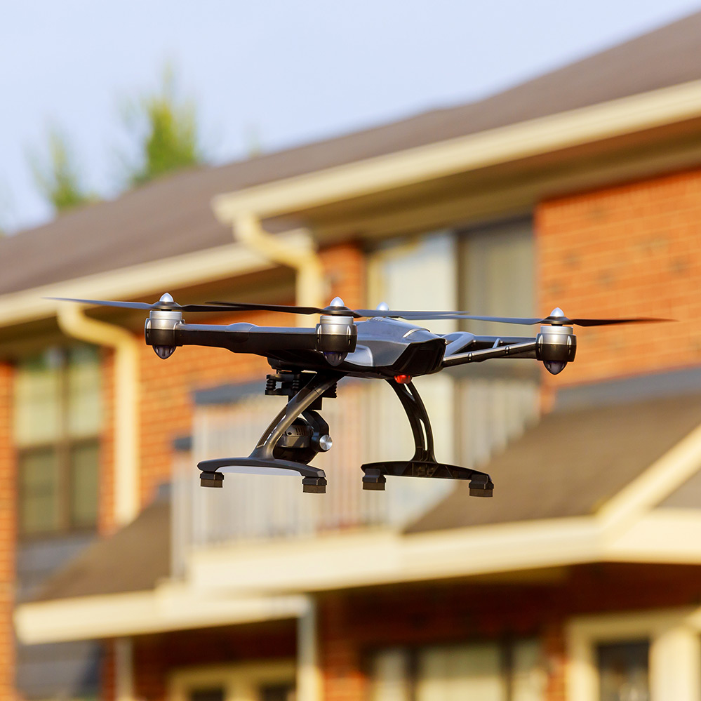 Drone flying by residential brick houses