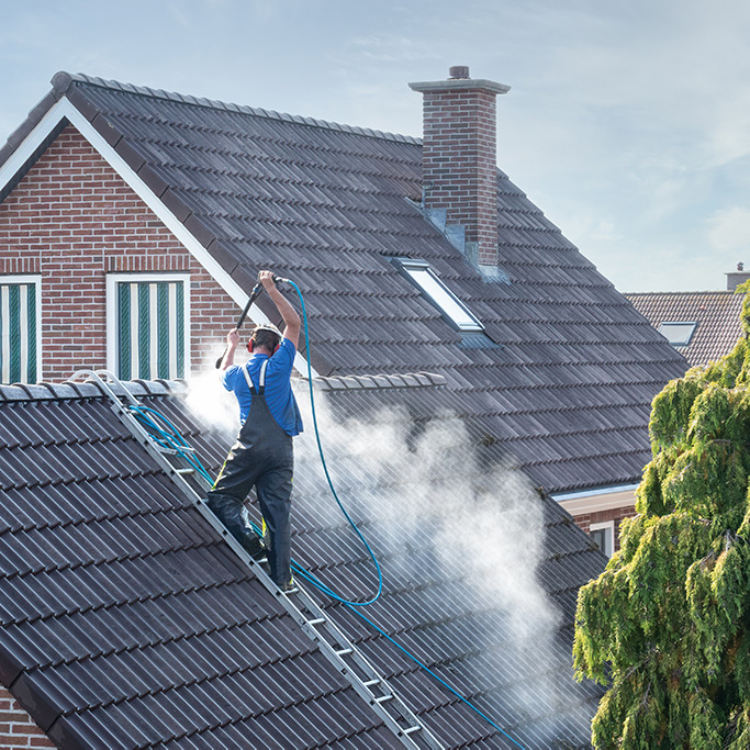 Man pressure washing roof tiles in Surrey