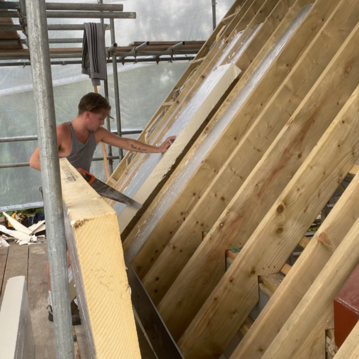 Sheltered roof with construction worker sawing wooden beam