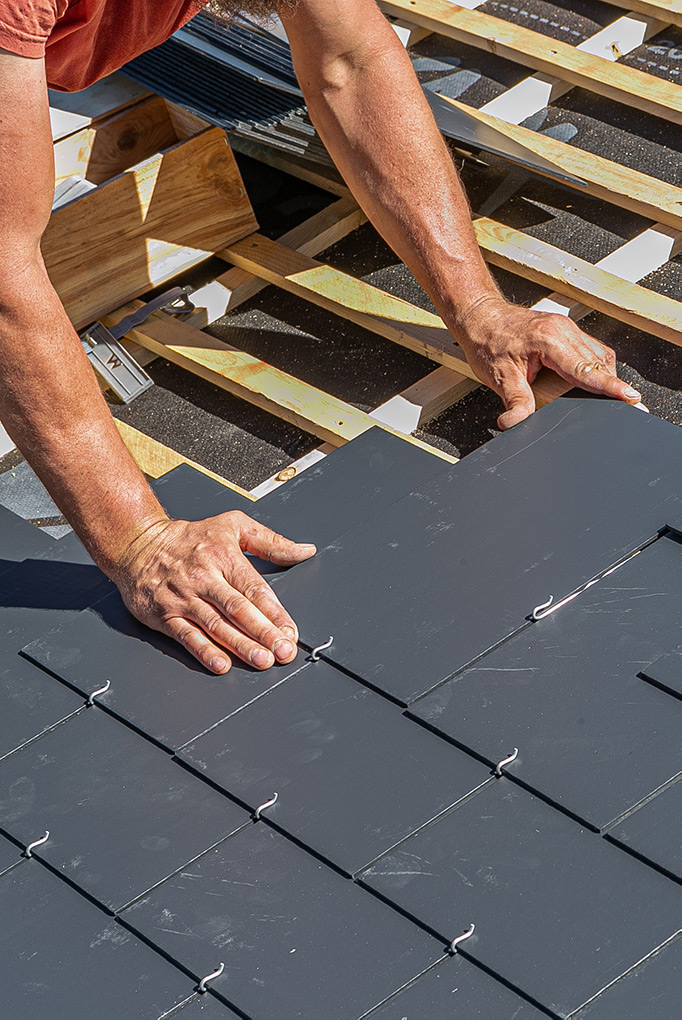 Roofer installing tiles on roof